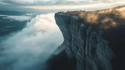  Majestic cliff overlooking a sea of clouds at sunset, with a serene landscape in the background © Amartv17