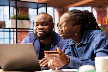 Pleased people making reservations for a family vacation on the pc, entering bank credentials to approve a payment and booking a trip with hotel room. Confident people organizing travel plans.