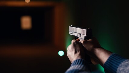 Man holding pistol enjoying recreational indoor shooting experience in firing range facility, close...