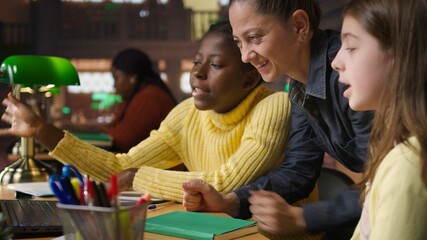 Multiethnic scholars in the library engaged in remote learning with their mentor, participating in a video conference with other students for an assignment. Pupils attend online webinar. Camera A.