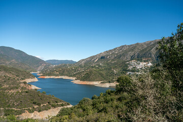 Obraz premium Panoramic view of mediterranean landscape with mountains and river under clear blue sky, La Concepcion reservoir in Marbella