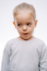 Naklejka premium Portrait of a little surprised girl with her mouth open looking to the side on a gray background