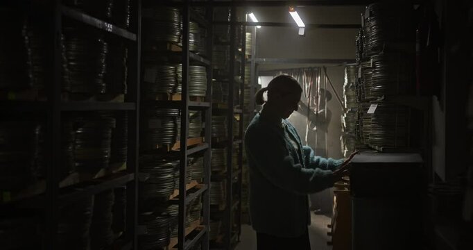 Elderly Couple Searching for Lost Film Reels in a Vintage Archive
