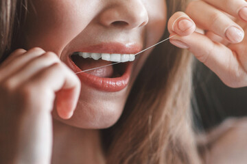 Unrecognizable young girl cleaning teeth with dental floss, close up. Panorama