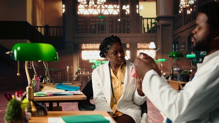 Dentistry students team doing research with plastic human jaw model in a library, preparing for exams on oral hygiene and stomatology. Learning tools for a successful dental career. Camera A.