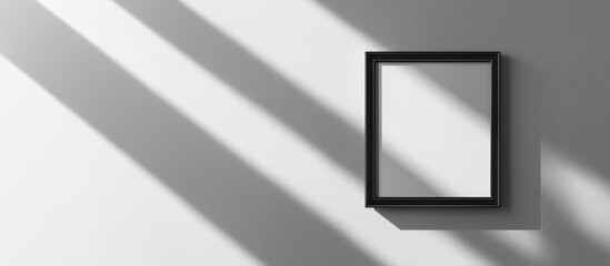 A black framed picture hanging on a white wall with shadows