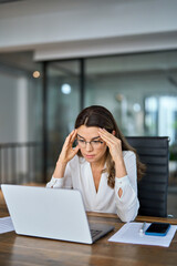 Tired stressed mature business woman wearing glasses having headache at work feeling pain or...