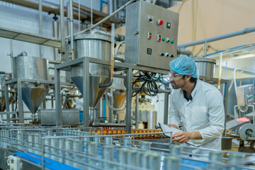 A factory worker inspects advanced machinery in a modern food production facility, ensuring...