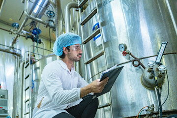 Technician in protective gear evaluating a production tank, representing quality assurance, meticulous processes, and expertise in industrial manufacturing.