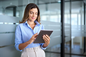 Busy middle aged businesswoman manager, older female executive leader holding pad digital tablet at...