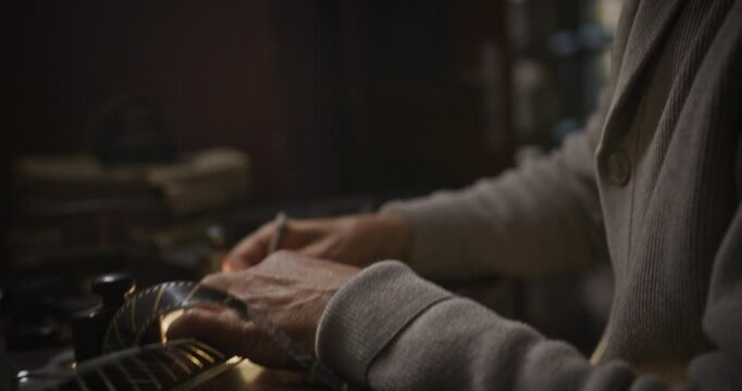 Film Editor Inspecting Vintage Film Reel on Editing Table