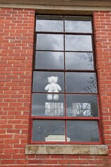 Faceless teddy bear in window of abandoned building