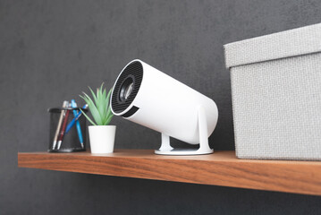 White projector with a lens on shelf
