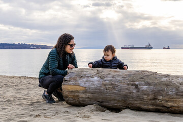 Fototapeta premium Woman and Child Enjoying a Beachfront Log at Stanley Park, Vancouver, Canada