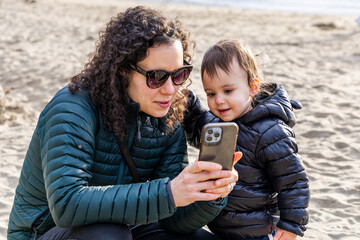 Mother and Child Enjoying Quality Time Viewing Phone at Stanley Park Beach