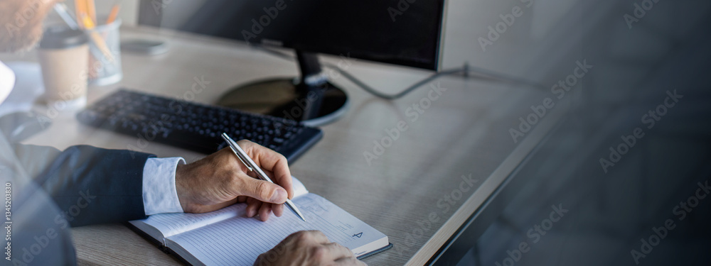 Fototapete close up of businessman sitting at desk, working online while using computer and taking notes at off
