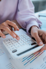 Hands using a calculator and pen on financial documents, ideal for business, finance, and accounting themes.
