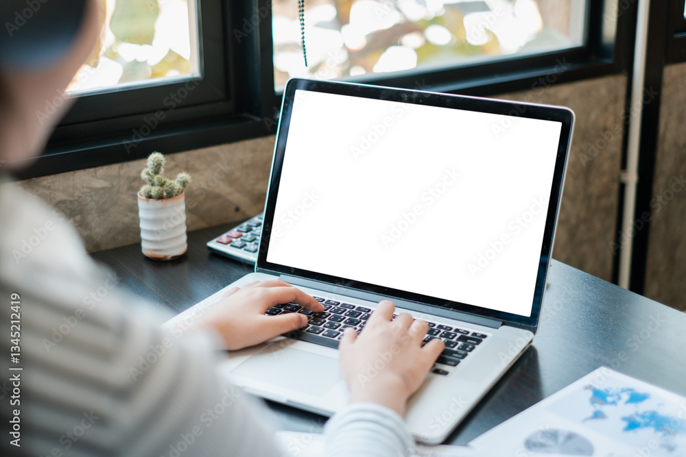 Poster hands typing on a laptop with a blank screen, placed on a desk by a window, featuring a small cactus