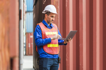 Logistics professional with laptop inspecting containers, Engineer man checking containers box in in Industry containers yard