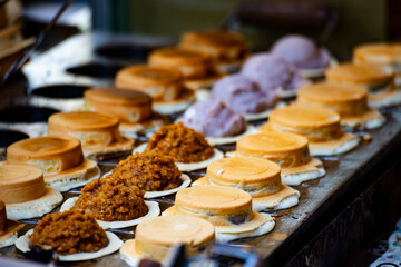 a vendor in the process of making hot and steaming wheel cakes
