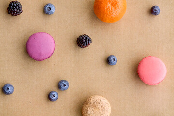 Colorful Macarons with Berries and Citrus on Plain Background