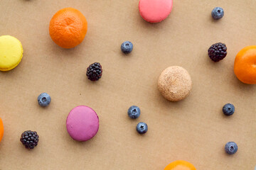 Colorful Macarons with Berries and Citrus on Plain Background