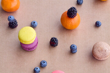 Colorful Macarons with Berries and Citrus on Plain Background