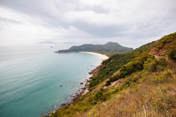 Fototapeta premium Serene Coastal Landscape with a Curved Beach in a Cloudy Day