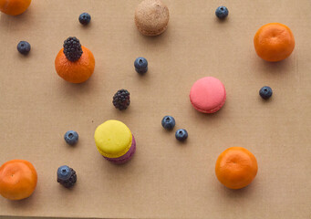 Colorful Macarons with Berries and Citrus on Plain Background