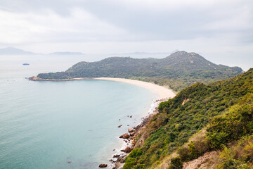 Serene Coastal Landscape with a Curved Beach in a Cloudy Day