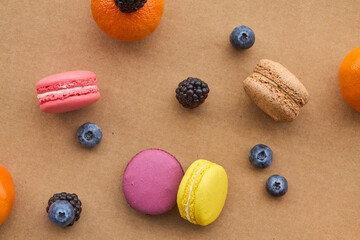 Colorful Macarons with Berries and Citrus on Plain Background