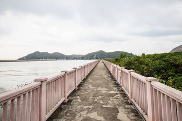 Obraz premium Long Concrete Bridge Leading to Distant Hills on Cloudy Day
