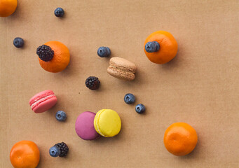 Colorful Macarons with Berries and Citrus on Plain Background