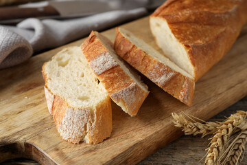 Pieces of fresh baguette and spikes on wooden table, closeup