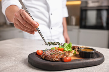 Professional chef serving dish at table indoors, closeup