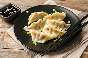 Delicious gyoza dumplings with chives served on wooden table, closeup