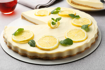 Tasty lemon cheesecake with mint on grey textured table, closeup