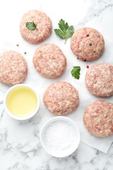 Many uncooked patties and spices on white marble table, flat lay