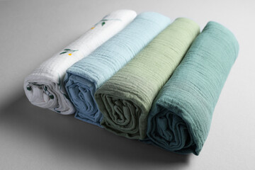 Rolled baby blankets on light grey background, closeup