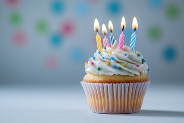 Cupcake with lit candles and colorful sprinkles.