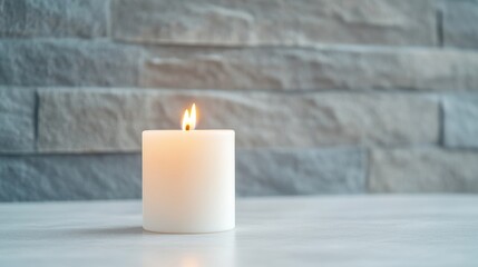 Single white candle flame on a light surface in front of a gray stone wall