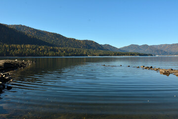 A small bay surrounded by sand spits on the shore of a beautiful mountain lake on a sunny autumn...