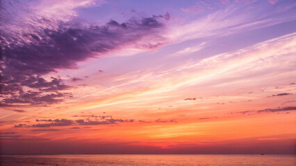 Fototapeta premium A breathtaking sunset over a calm sea, painting the sky with vibrant hues of orange, purple, and pink, creating a serene and magical atmosphere.