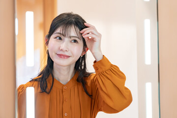 鏡を見てヘアチェックをする女性