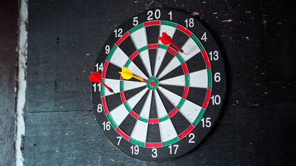 dart board hangs on a black wall with darts stuck into it