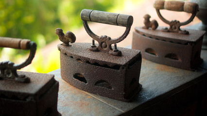 Antique rusty charcoal iron for ironing clothes with wooden handle stands o..