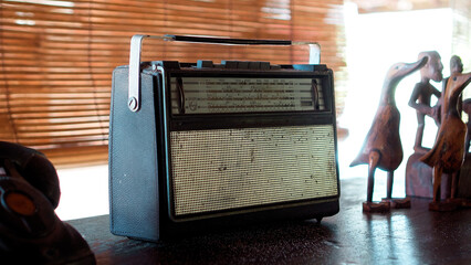 An antique radio with analog controls sits on a wooden shelf
