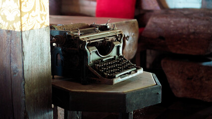 Antique cast iron typewriter with mechanical keyboard stands on wooden table