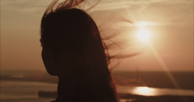 Woman hair blowing in wind at sunset by the river