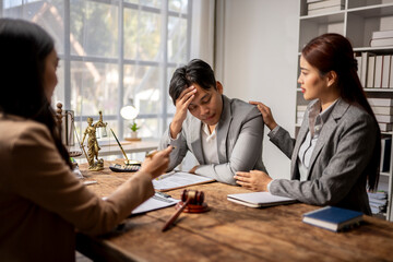 A man sits at a table with two women, one of whom is holding his hand